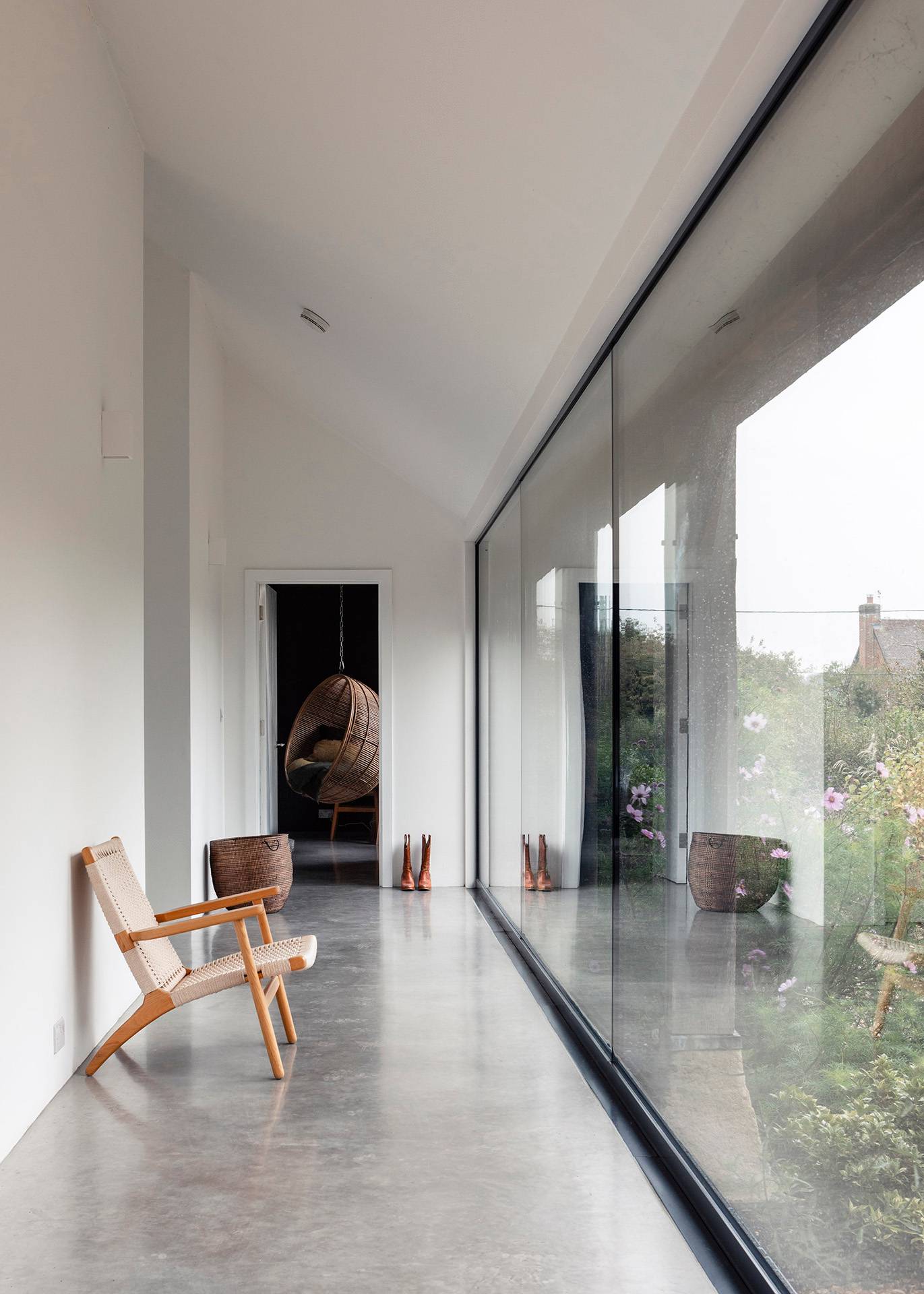 Minimalist hallway gallery corridor framed by floor-to-ceiling glass windows and polished concrete floors, Love Locations SN8.