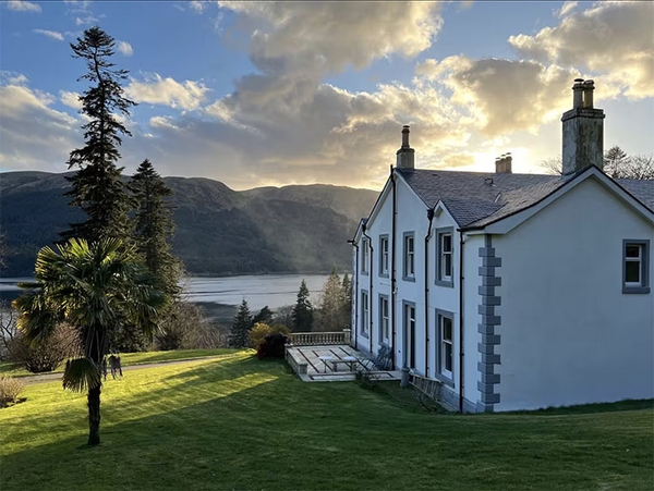 Glenstriven estate exterior at dusk with historic country house, loch-view lawn and mountains.