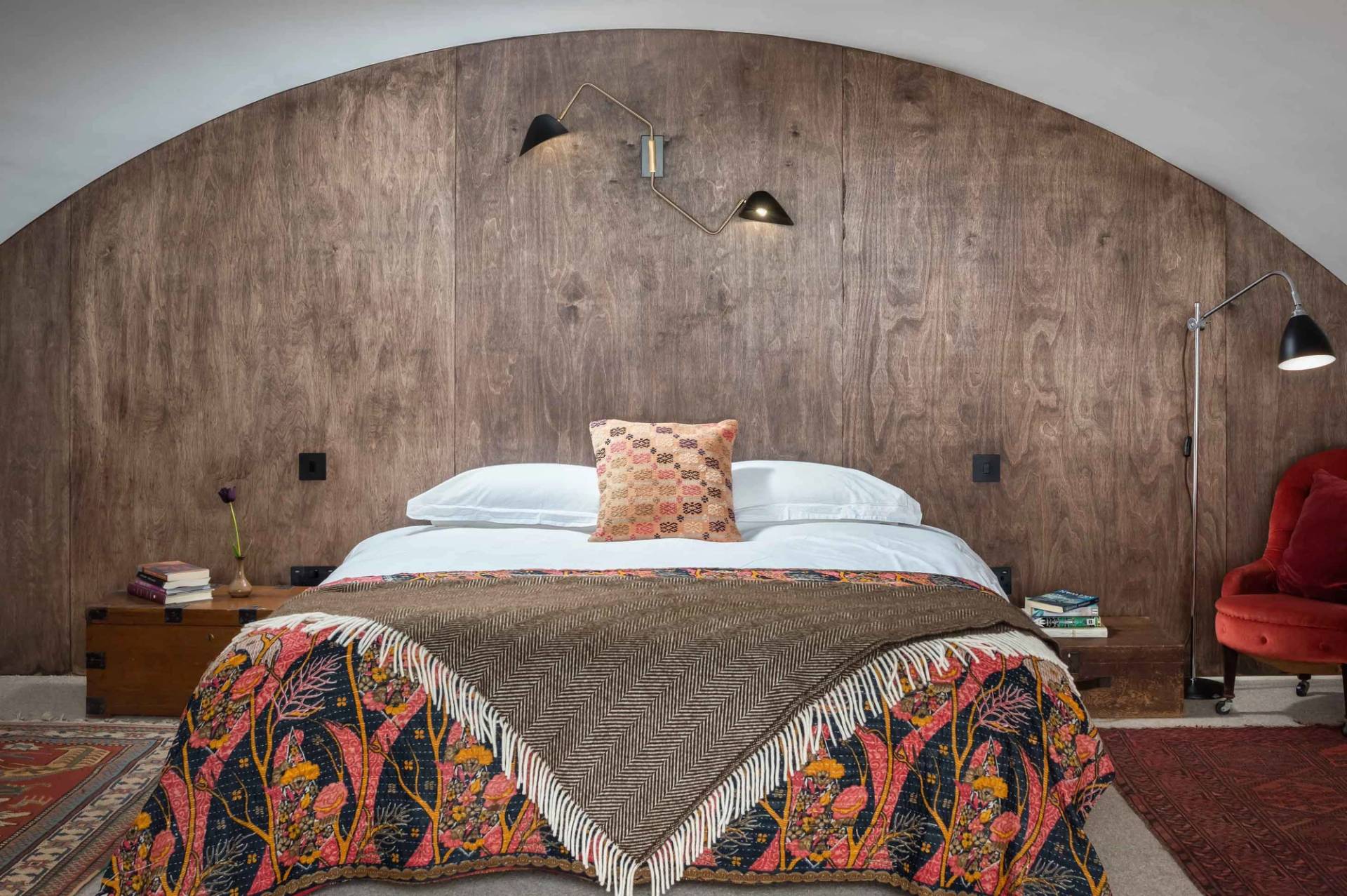 Boutique bedroom film location in Ipplepen Totnes Devon TQ12 via Love Locations, featuring an arched rustic wooden headboard wall and patterned textiles.