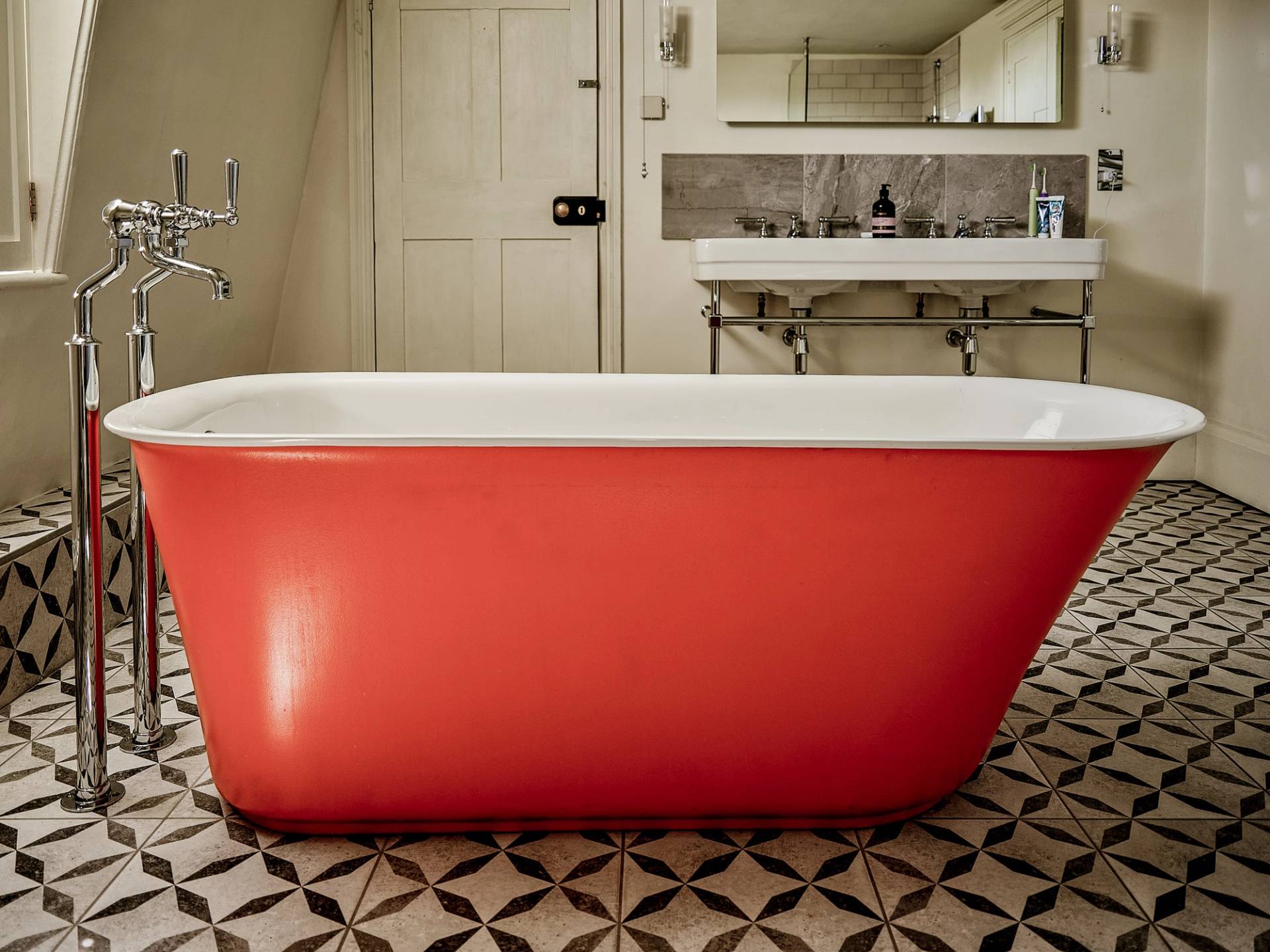 Terracotta orange freestanding bath tub set on geometric floor tiles in a Georgian home, Love Locations ME13.