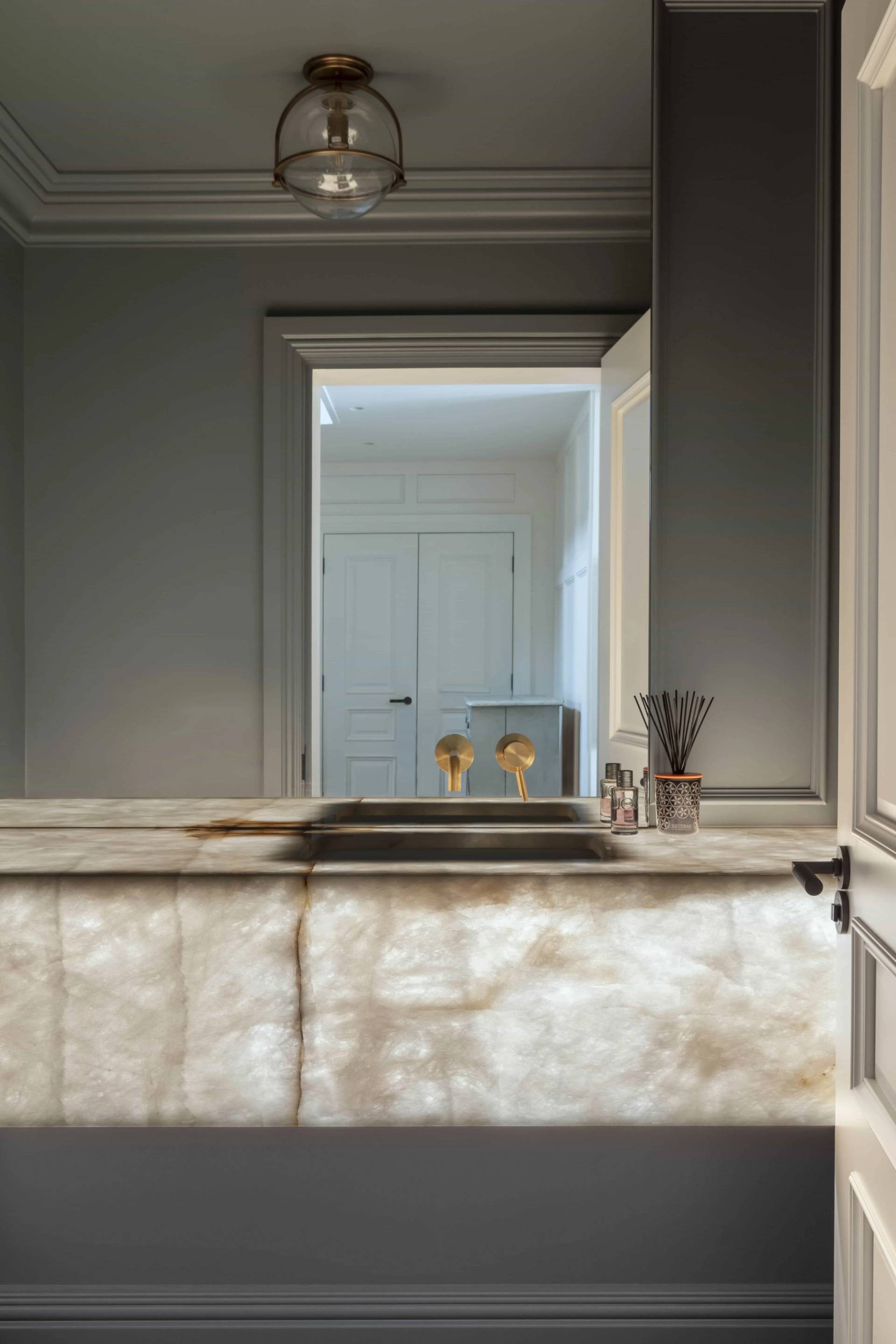Marble-topped bathroom vanity reflected in a large mirror framed by dark grey walls, Love Locations HP18.
