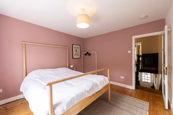 Love Locations cozy bedroom setting East London: Softly lit pink hued guest bedroom showing an open, airy residential atmosphere, perfect for domestic scenes in TV series and independent film.