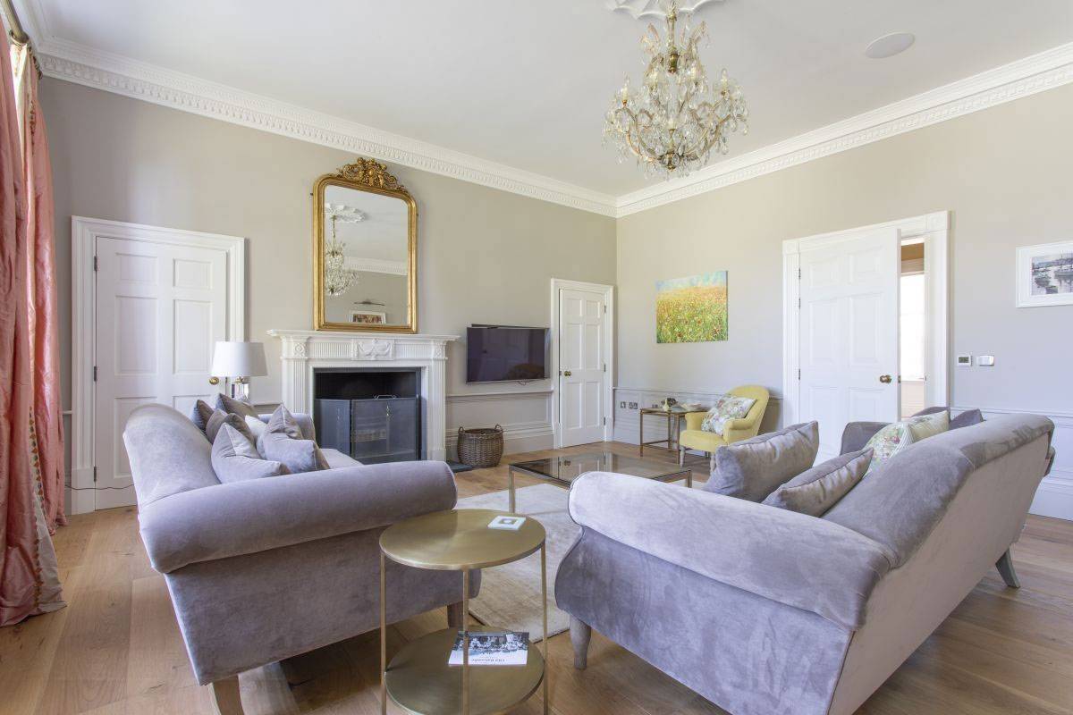 Elegant Georgian living room with plush grey sofas, marble fireplace, and ornate chandelier available for filming via Love Locations, Haywards Heath, RH17.