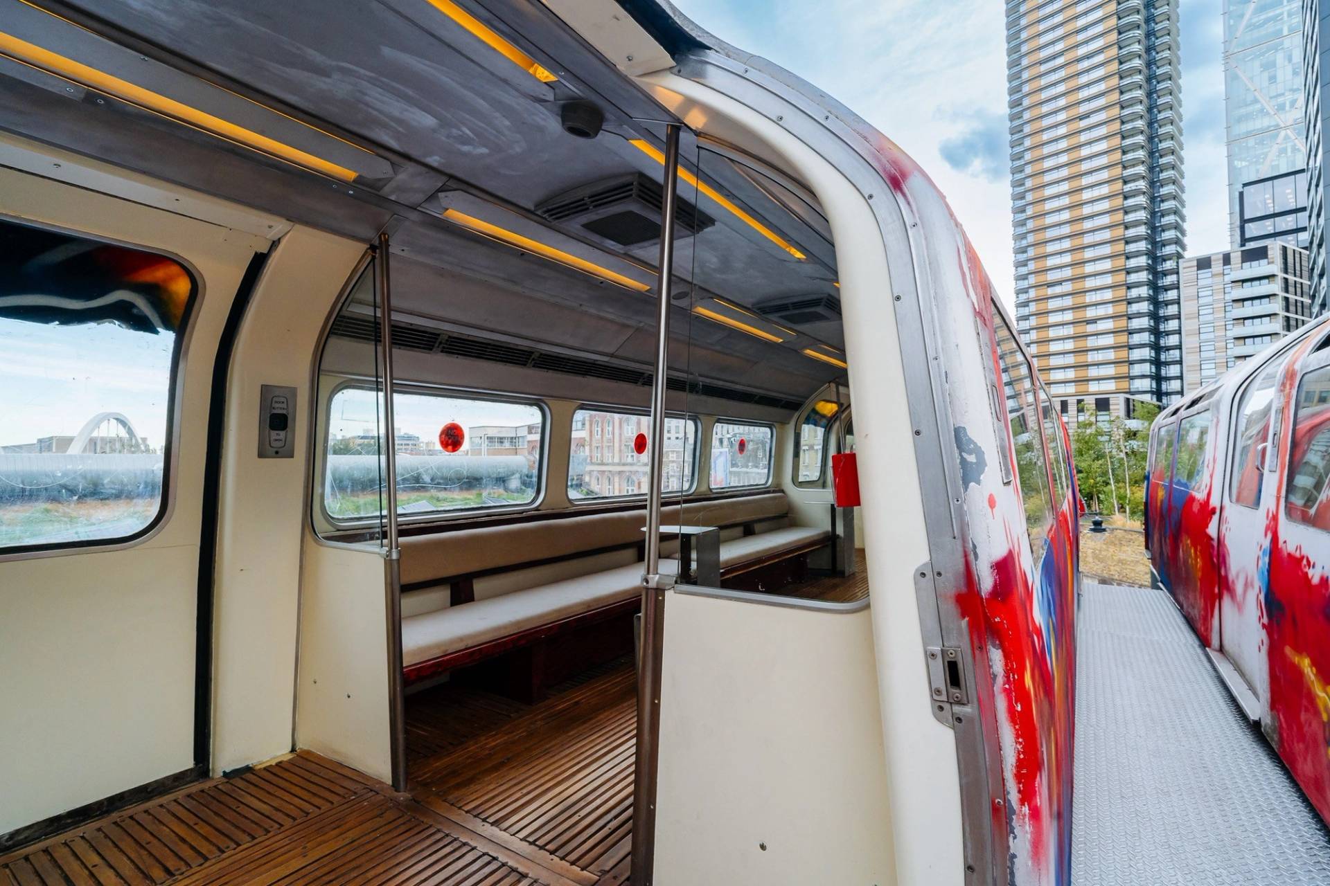 Converted train carriage interior location house in Hackney EC2A by Love Locations, featuring timber bench seating and large observation windows.