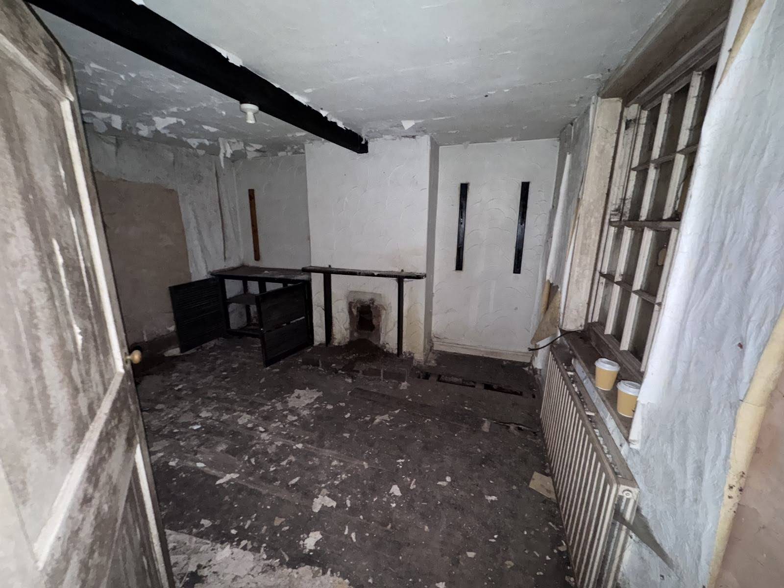 Grimy Victorian room with a simple fireplace hearth, old radiator, and soot-stained walls, a characterful filming location via Love Locations.