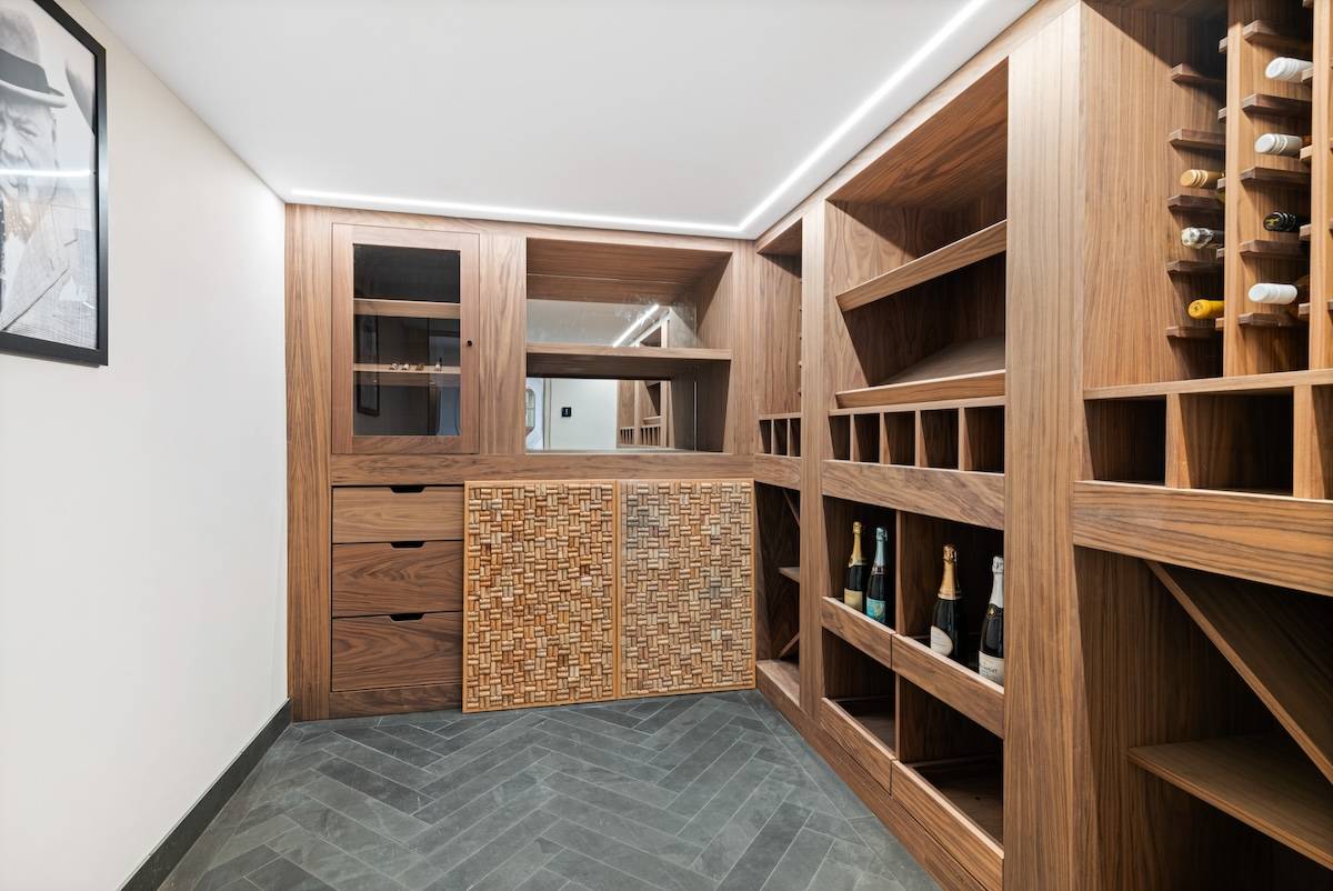 Custom wooden wine cellar storage room with built-in bottle racks and chevron floor tiles, Love Locations RH13.