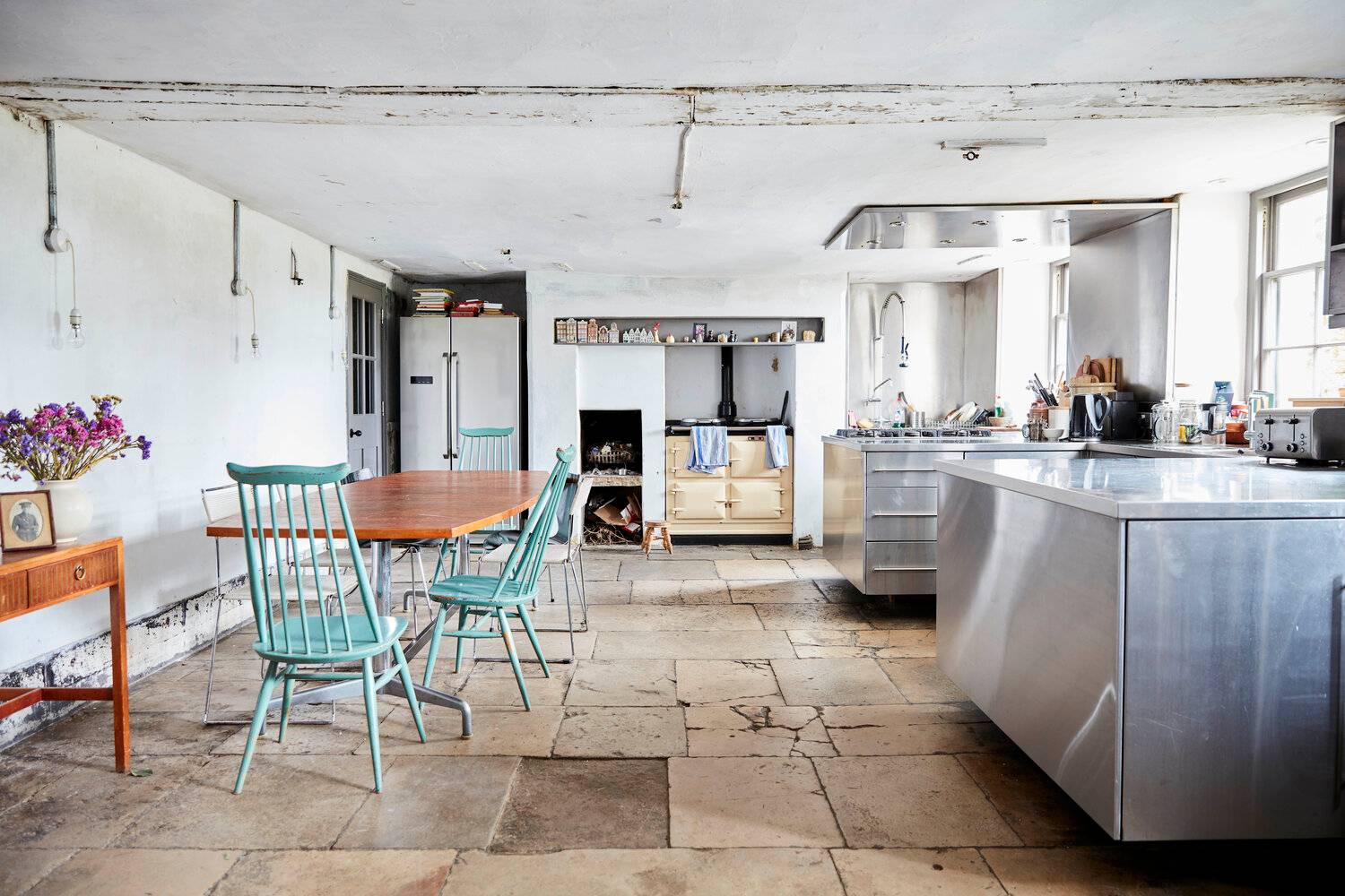 Industrial Scandi-style kitchen featuring flagstone floors, stainless steel island, and a beige AGA range cooker, ideal for culinary ads, Love Locations SE8.