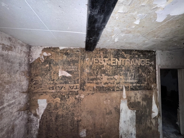 Close-up of decaying plaster walls showing historical faded stenciled text, an authentic texture backdrop for photo shoots via Love Locations.