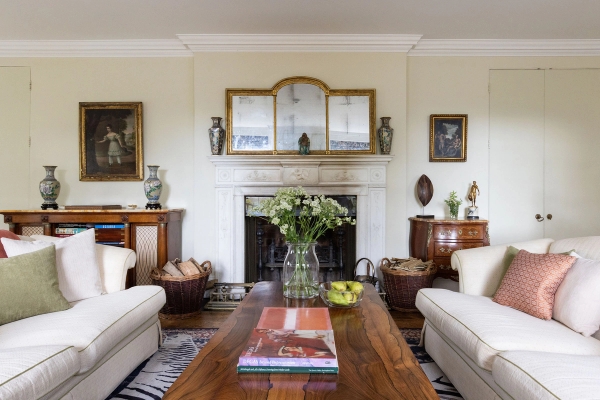 Love Locations period property film location Ashington West Sussex: Elegant white mantelpiece with a grand triptych mirror, log baskets, and antique oil paintings, tailored for atmospheric TV series filming.