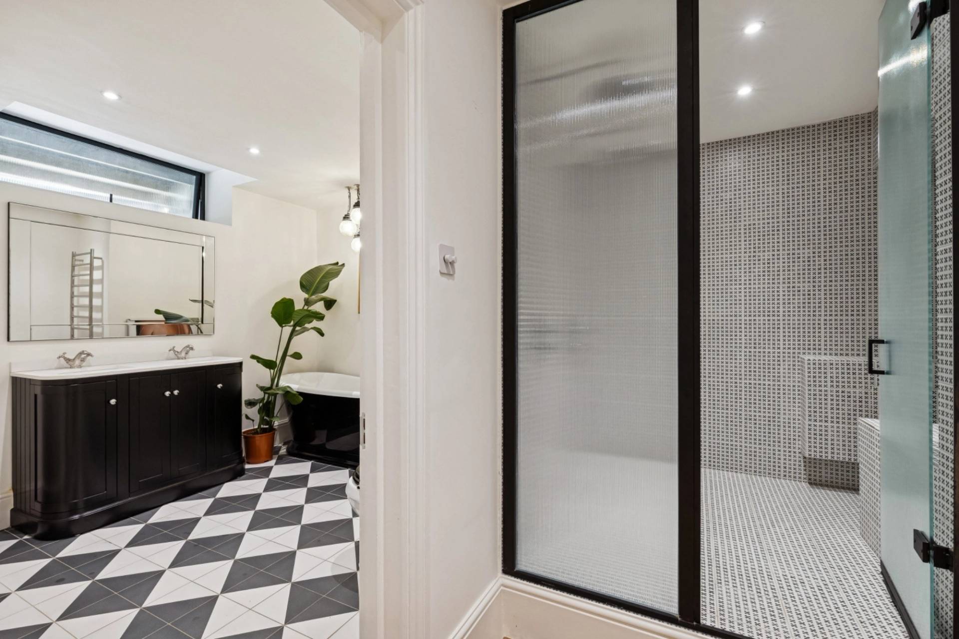 Black and white checkered tile bathroom with glass shower partition in Hampstead NW3 via Love Locations.