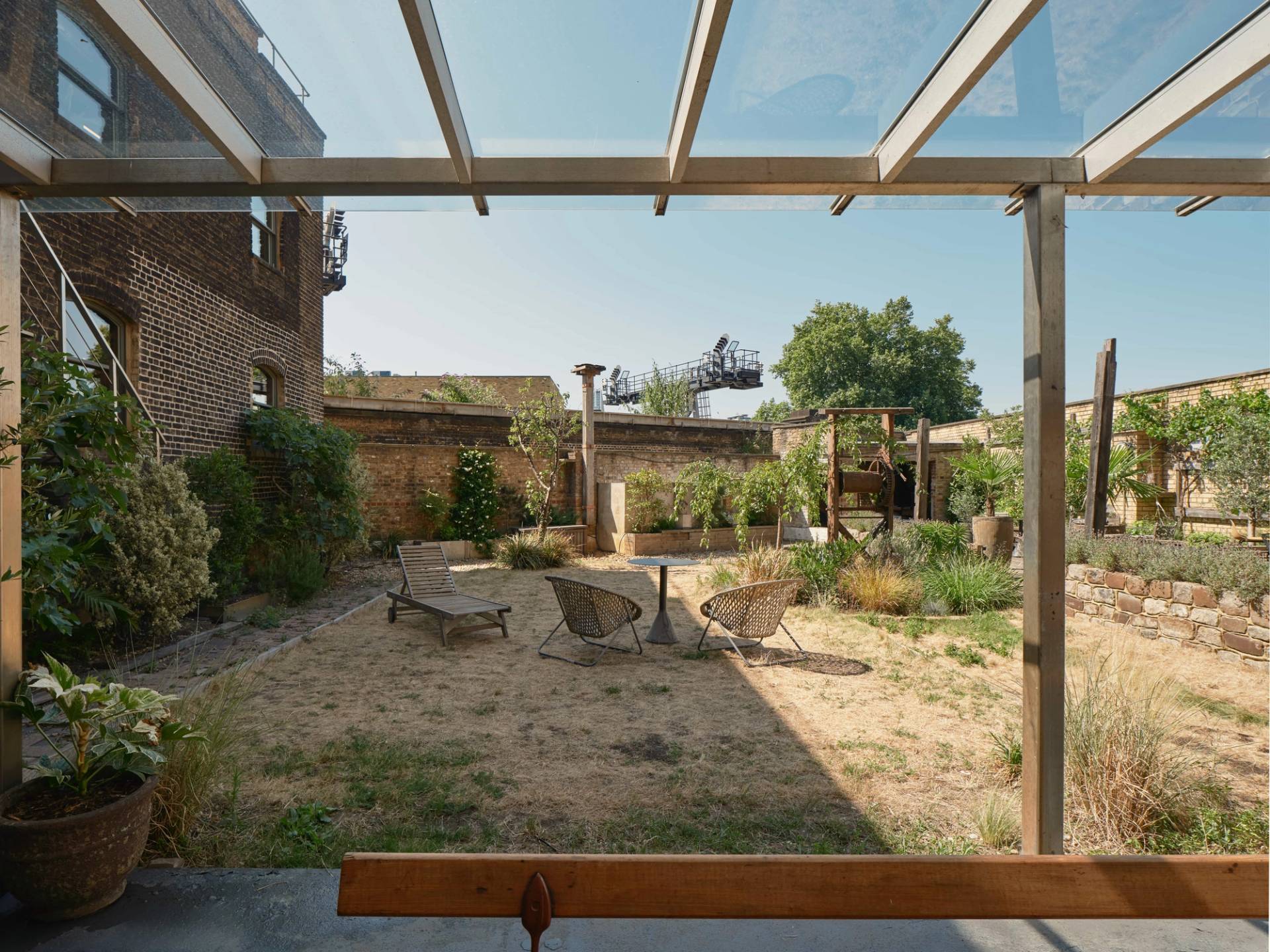 Private courtyard garden of The Lounge SE1 with seating, potted plants, and exposed brick walls.