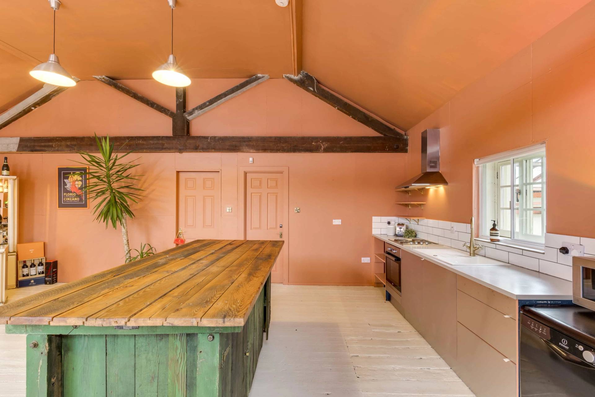Sleek minimalist kitchen production set with warm terracotta accent walls and wooden beams, Love Locations Richmond.