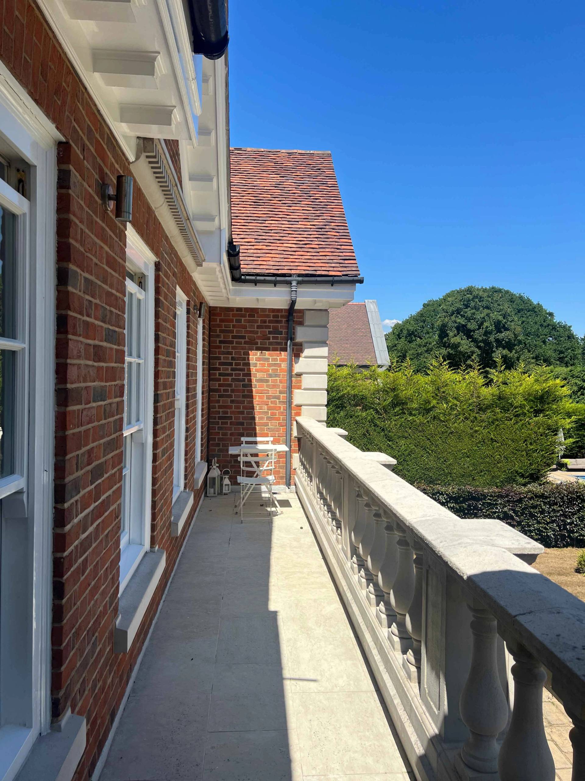 Upper floor balcony view showing stone balustrades overlooking red brick roof tiles and estate grounds, Love Locations BR7.