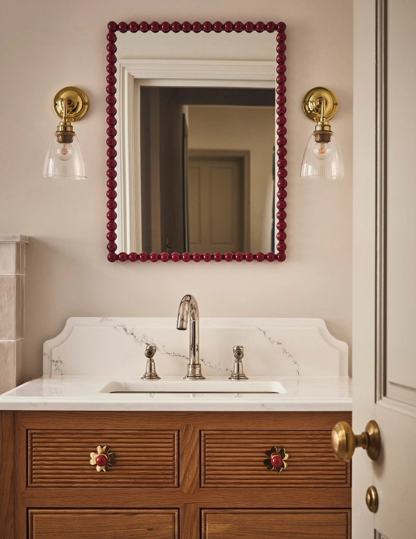 Bathroom vanity unit with a marble countertop, timber drawers, brass taps, and red framed wall mirror, Love Locations SE21.