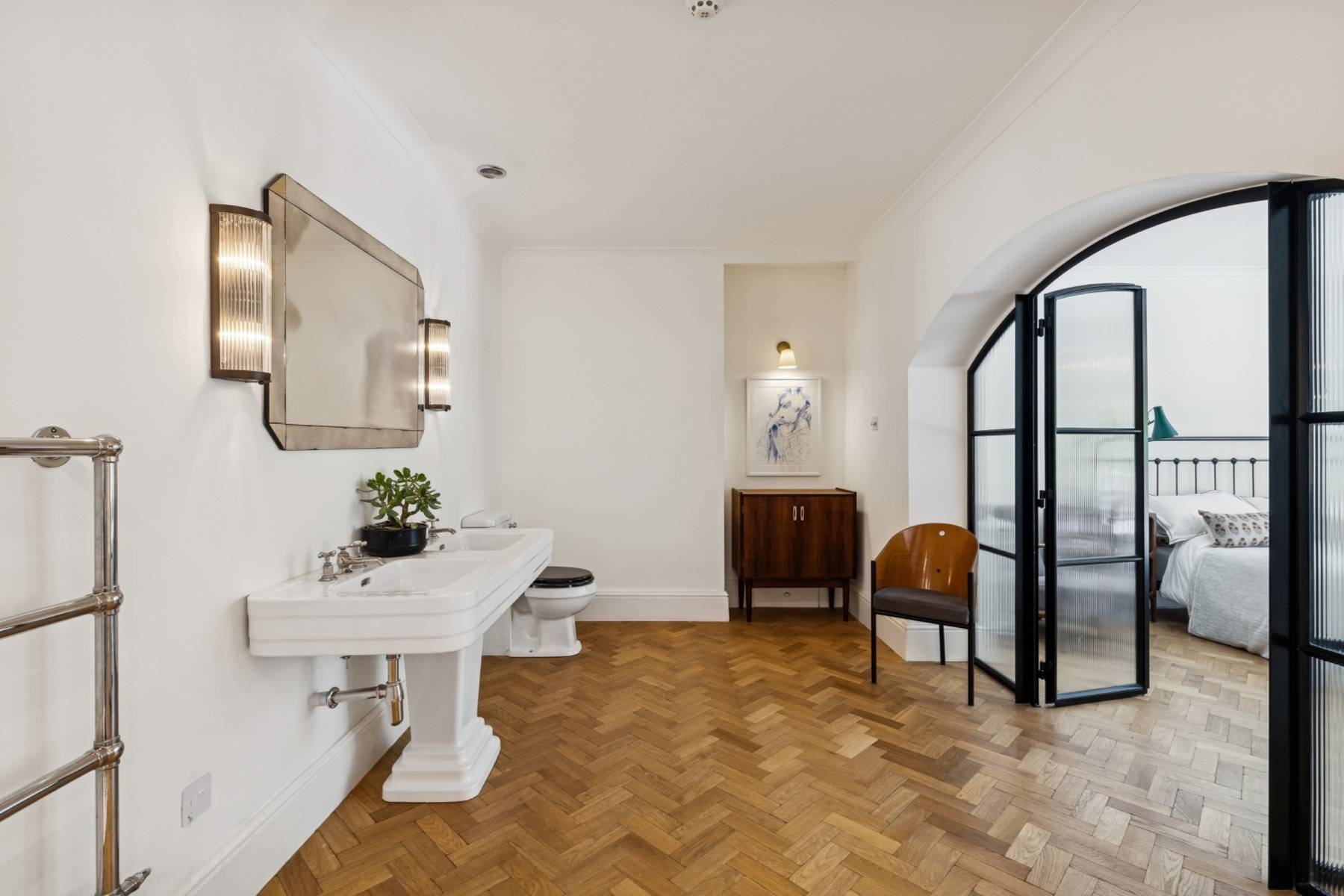 Modern bathroom location with pedestal sink, parquet floors, and black metal doors in Hampstead NW3 from Love Locations.
