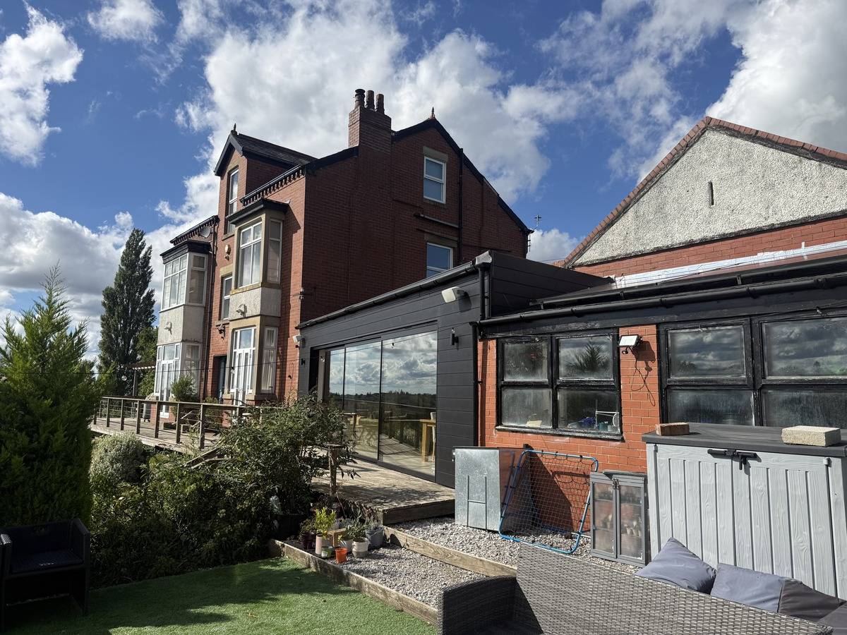 Rear exterior angle showing a modern glass extension and red brick facade in Stockport SK6 via Love Locations.