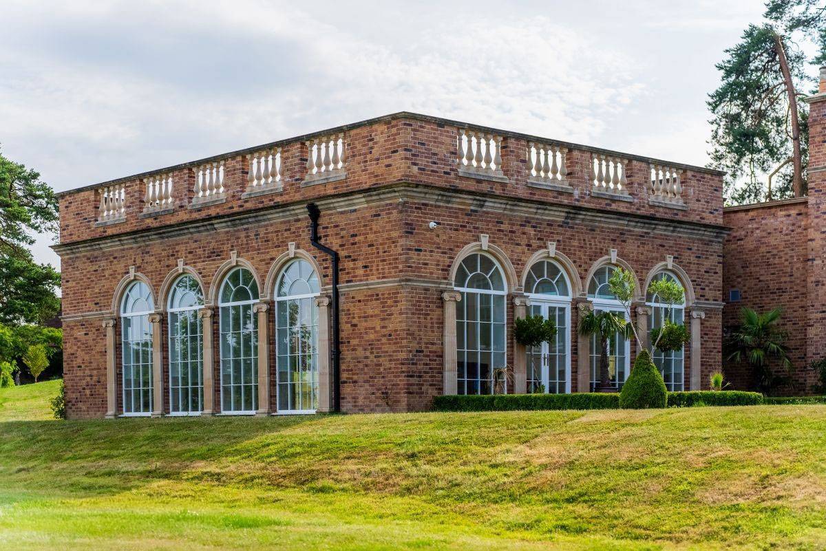 Stunning grand arched windows of a luxury orangery ballroom, perfect for high-end fashion shoots and product launches with Love Locations.
