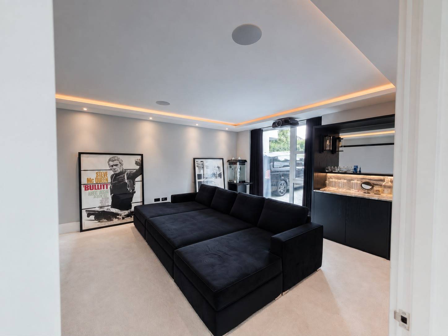 Dark moody home cinema and lounge shoot location in Barnet EN4 by Love Locations, featuring a deep black velvet sectional sofa and ambient perimeter ceiling lighting.