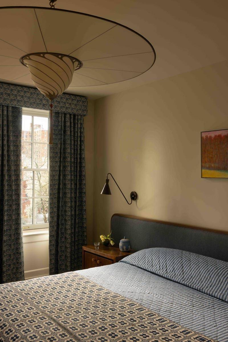 Serene master bedroom production location in a Brooklyn NY 11217 townhouse via Love Locations, with neutral walls, a large sash window with dark drapes, and sleek bedside lighting.