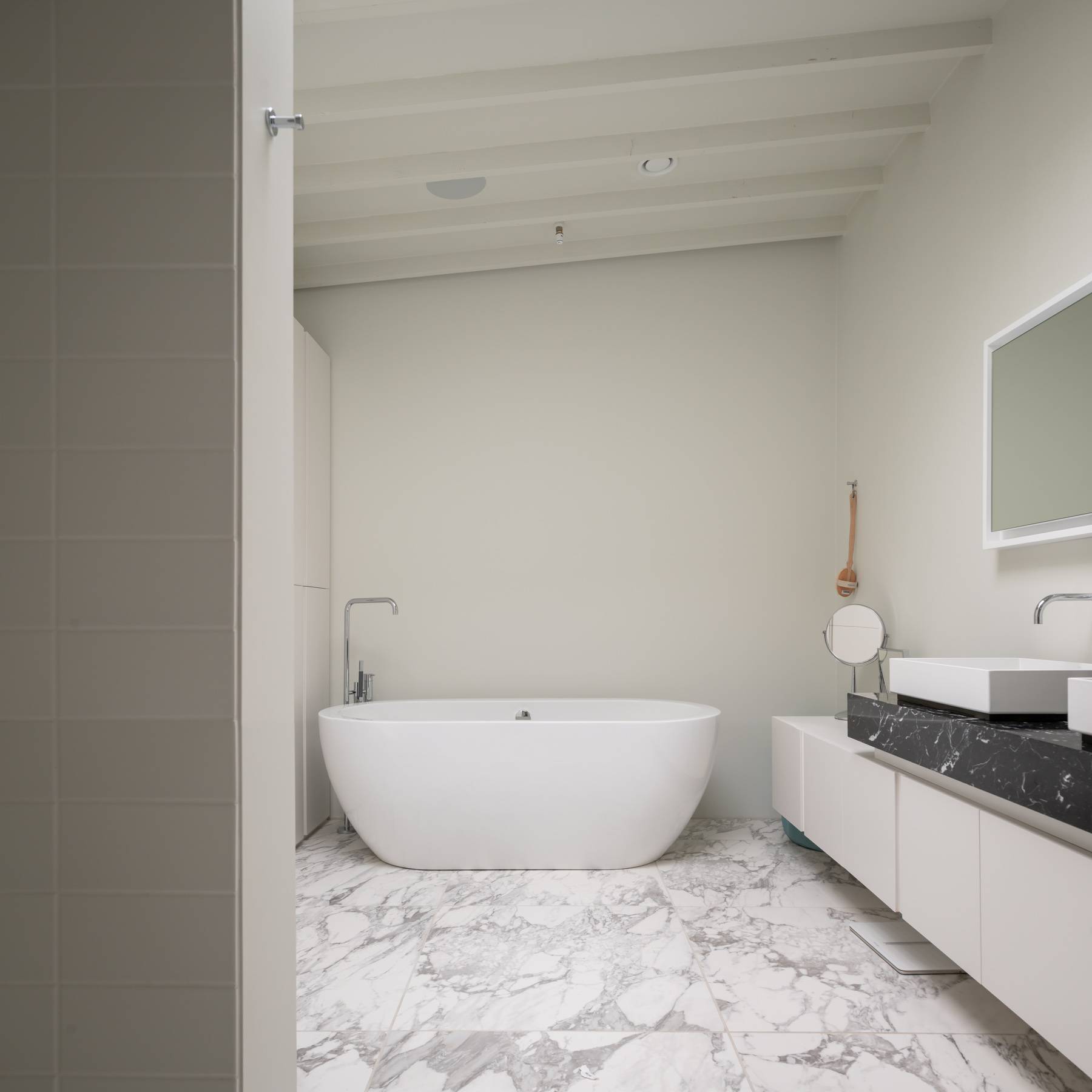 Luxury master ensuite featuring a freestanding oval bathtub set on white veined marble floor tiles, Love Locations BN3.
