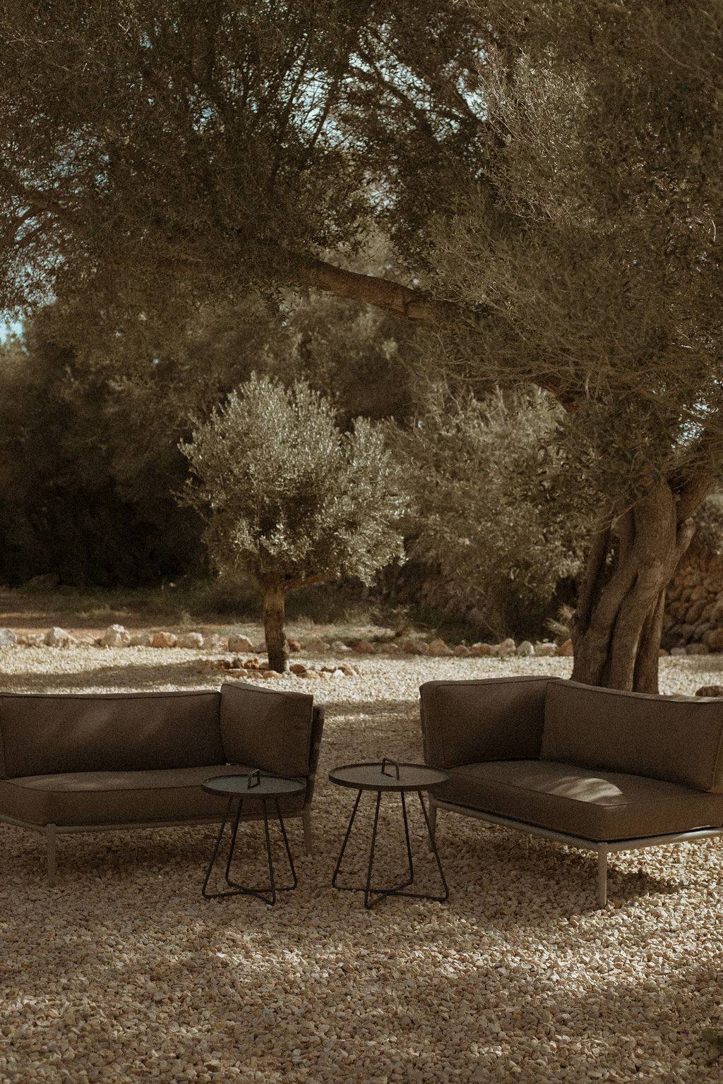 Outdoor lounge seating set under olive trees on a gravel garden patio, Love Locations 07630.