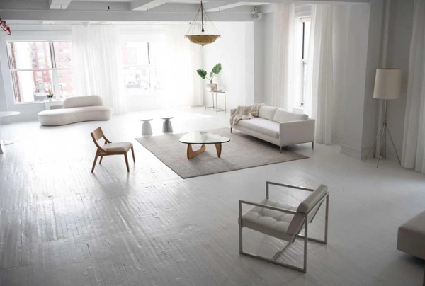Spacious white loft living area equipped with modern minimalist furniture and neutral area rugs, ideal for interior design catalog shoots, Love Locations.