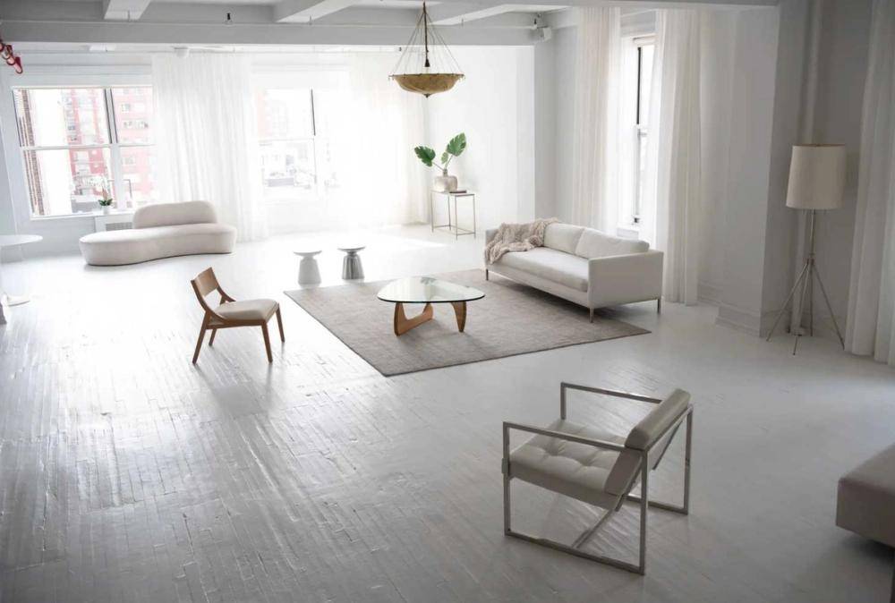Spacious white loft living area equipped with modern minimalist furniture and neutral area rugs, ideal for interior design catalog shoots, Love Locations.