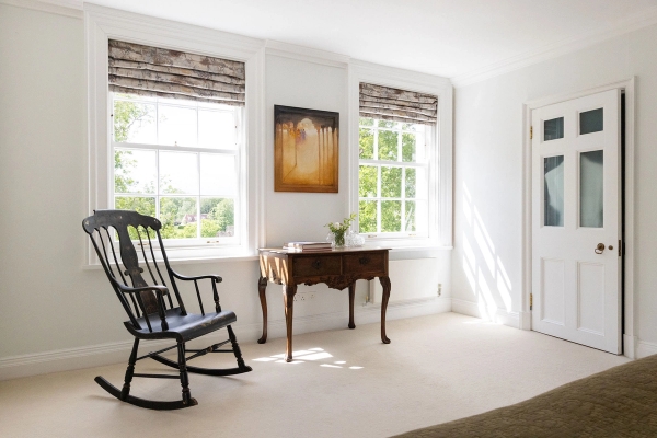 Love Locations characterful dressing room location Ashington: Bright corner space featuring a traditional black wooden rocking chair and antique side table, tailored for editorial portraiture.