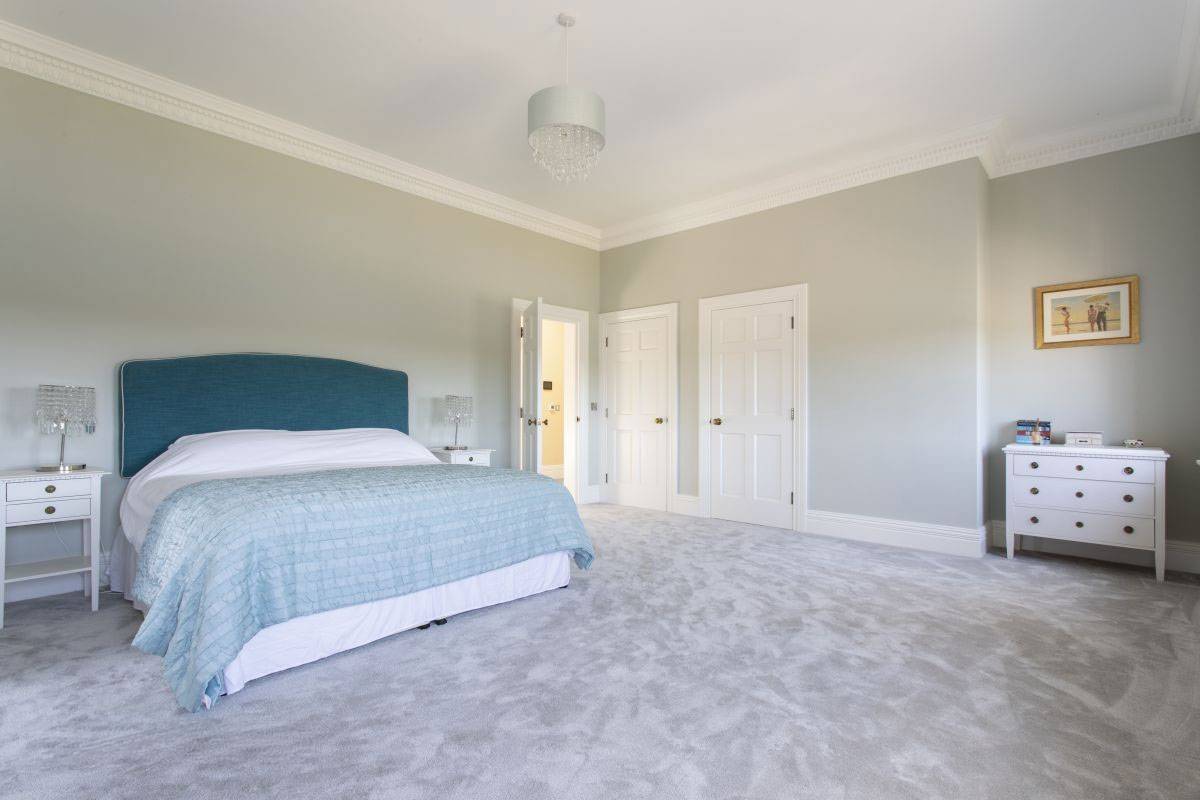 Bright, neutral-toned guest bedroom with traditional double doors and elegant styling for film production, listed by Love Locations.
