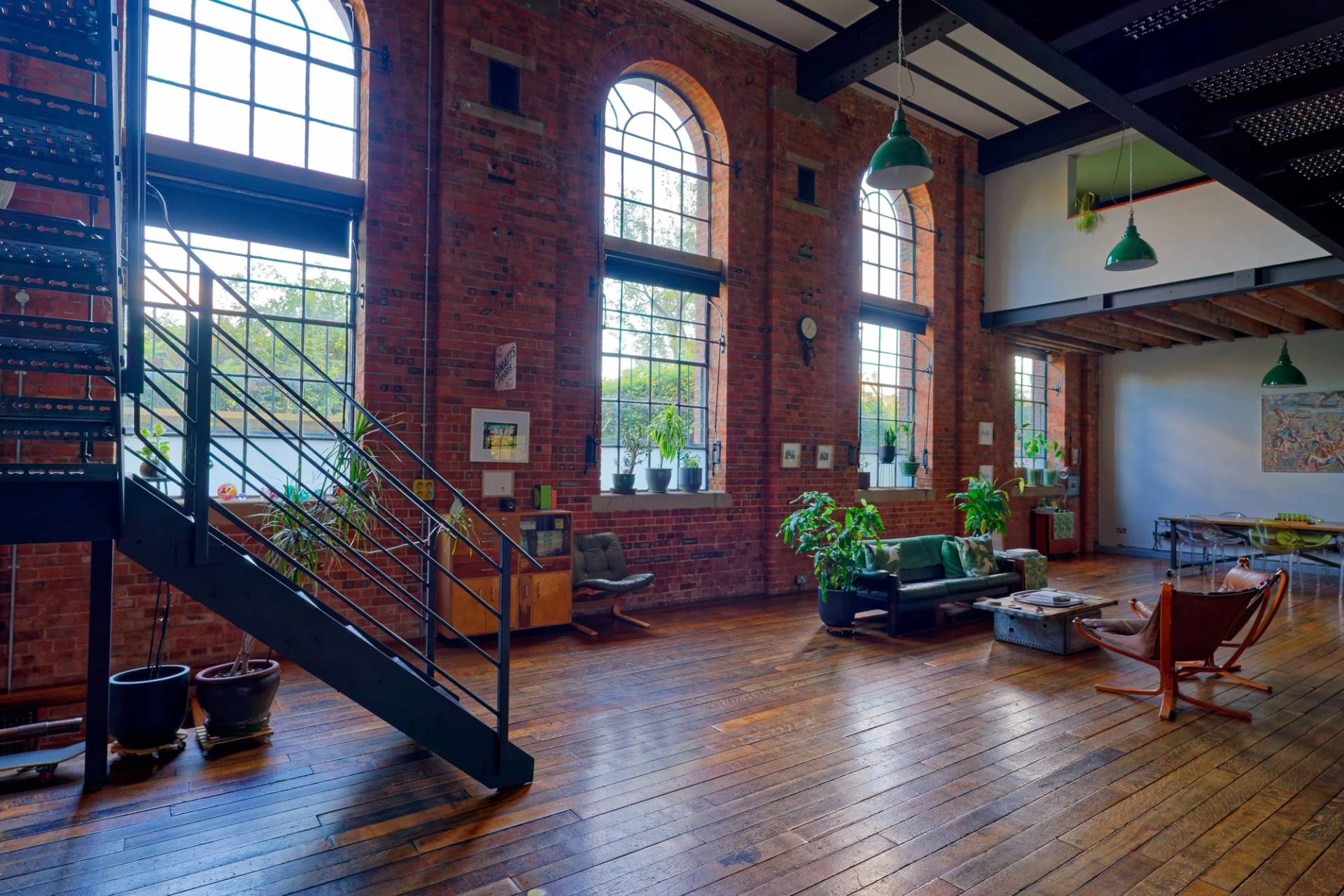 Spacious industrial hall with black steel staircase, vintage wooden storage chest, and large arched windows, Love Locations E14.