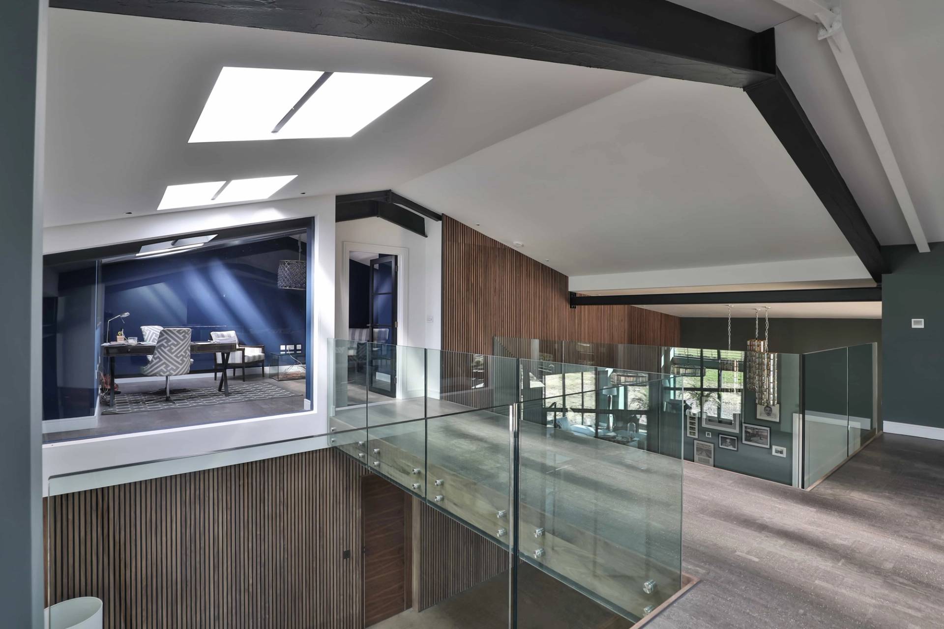 Mezzanine landing walkway with glass balustrades, skylights, and dark steel roof trusses, Love Locations CV23.