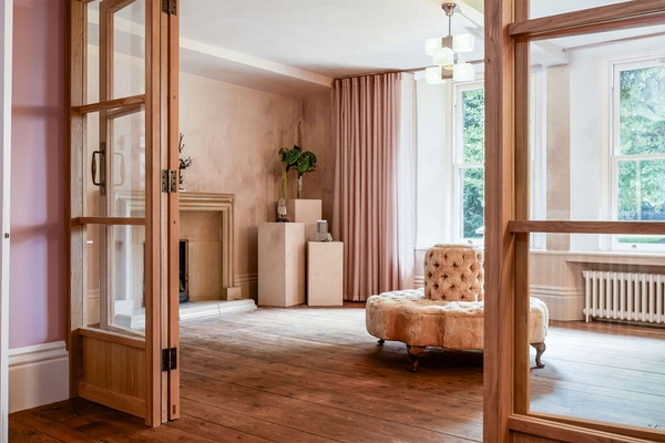 Glazed internal timber double doors looking through into a grand reception room with rustic wood flooring via Love Locations.
