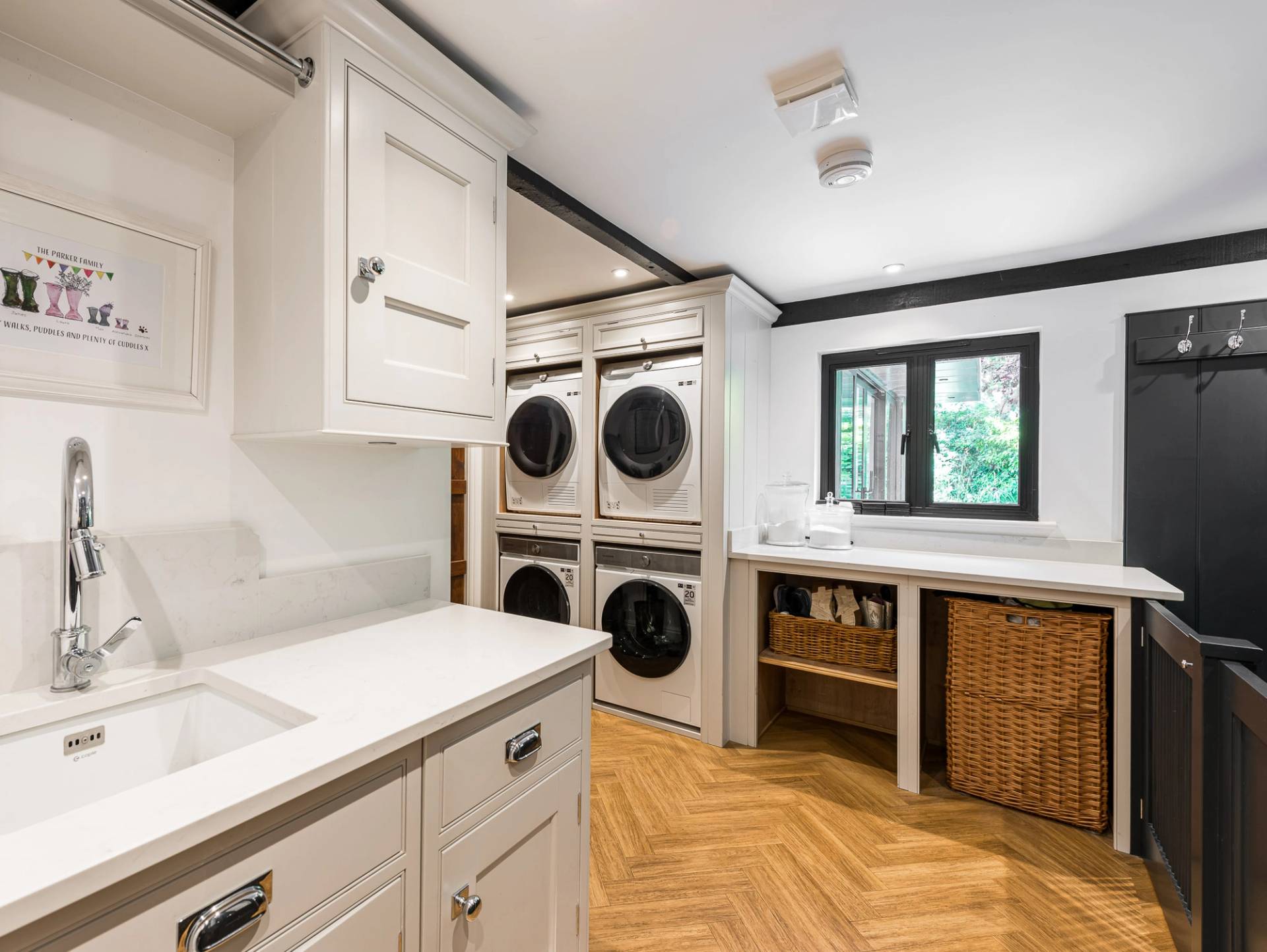 High-end residential utility room or laundry room location with stacked washing machines and oak parquet floors, Love Locations.