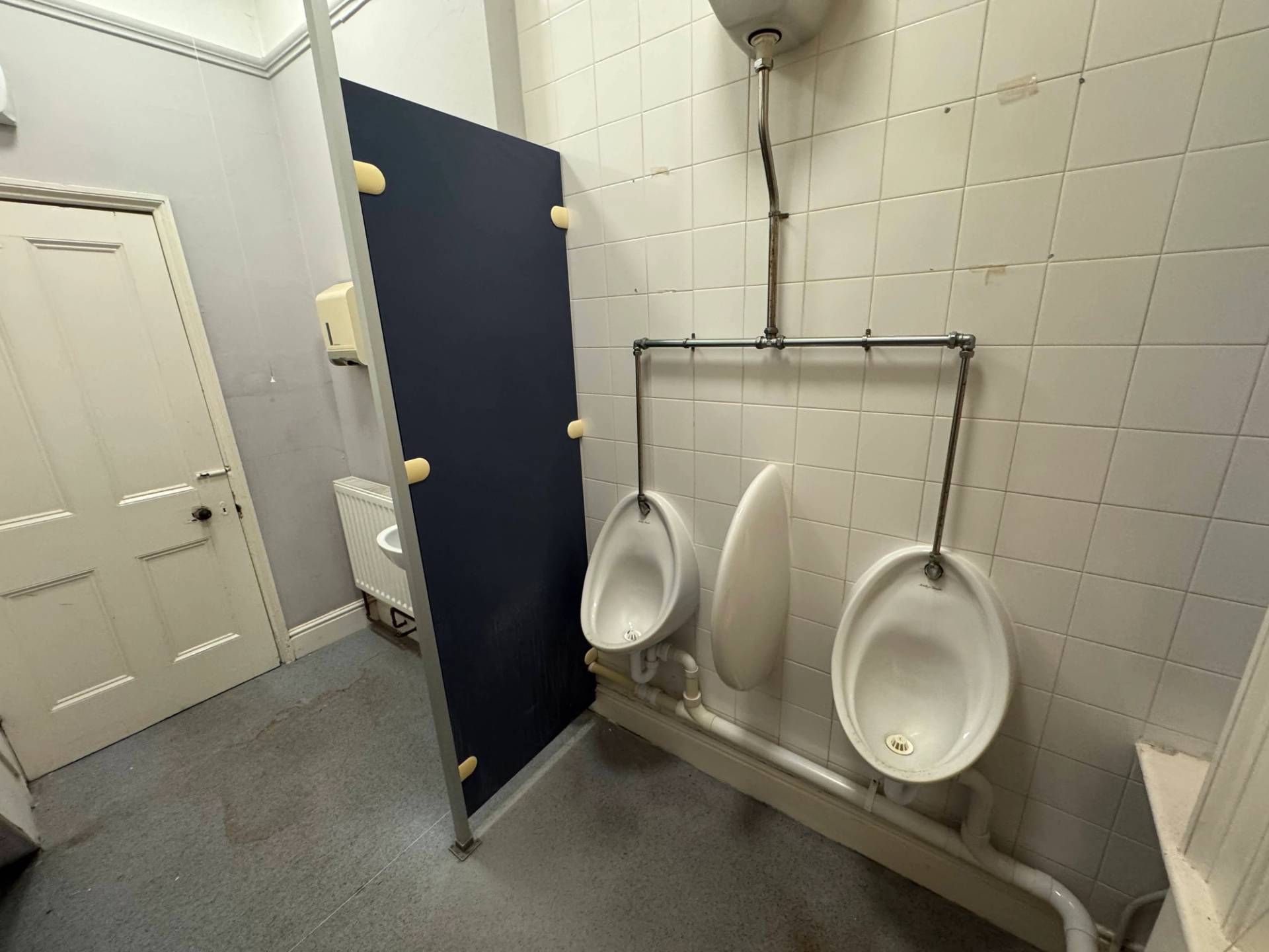 Gritty, unmodernised toilet block room with tiled walls and blue partition doors for realistic drama scenes, Love Locations.