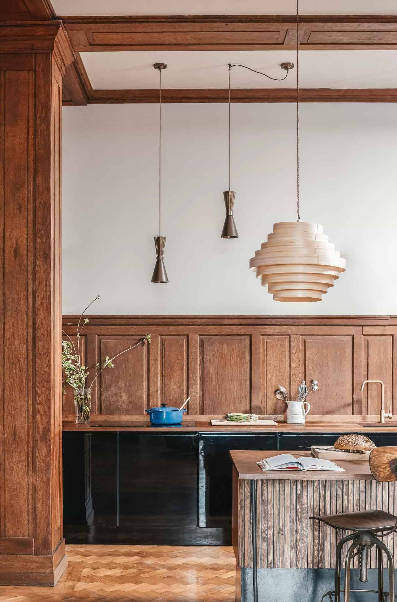 etail shot of a rustic kitchen counter with paper pendant lamps and dark wood panelling in a Devon location house through Love Locations.