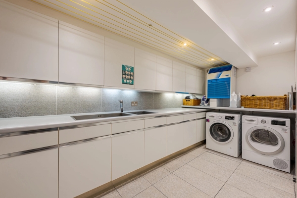 Sleek white utility and laundry room location equipped with long stainless steel countertops and modern appliances, suitable for home product marketing, Love Locations W4.