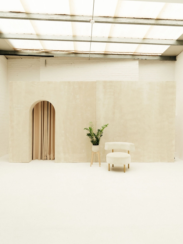 Romantic wedding backdrop with brushed plaster arched wall and curtain at Love Locations Brixton Warehouse.