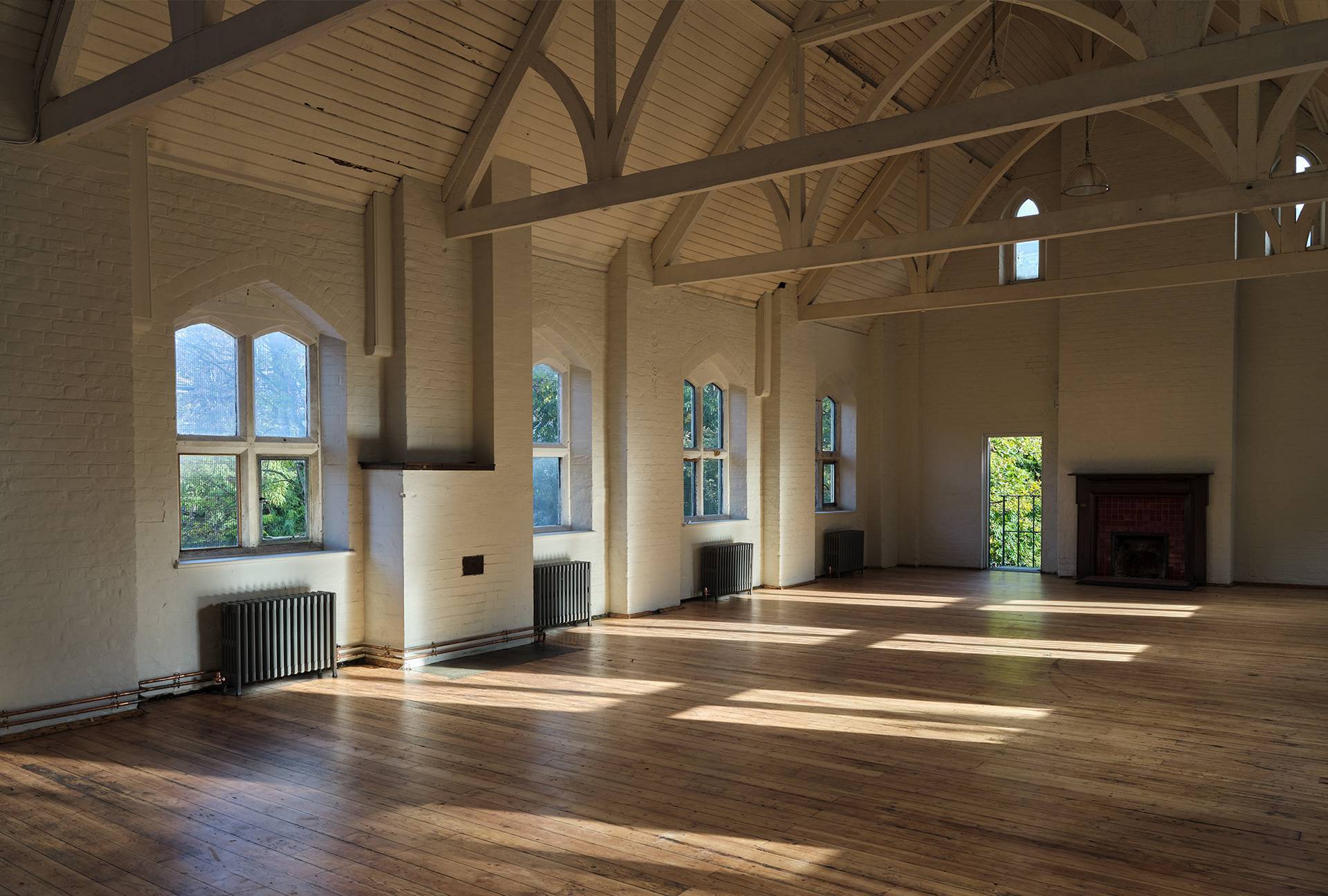 Bright hall interior with sunlight casting geometric window shadows across polished timber floors, Love Locations E2.