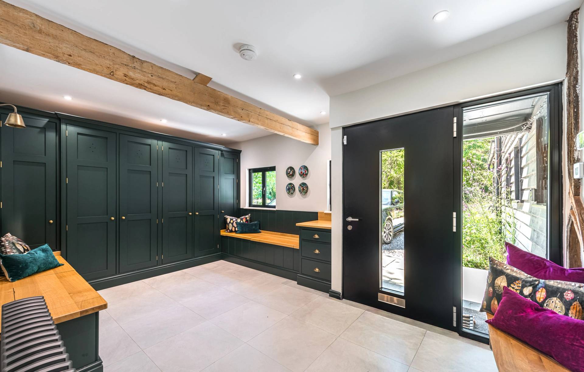 Spacious boot room and entrance hallway location with dark green cabinetry and exposed rustic timber beams, Love Locations.