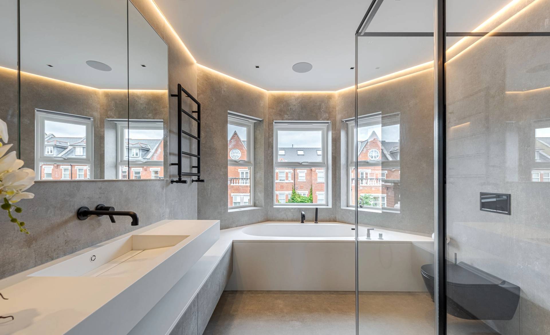 Master bathroom featuring a sunken bathtub set beneath bay windows with LED accent lighting, Love Locations SW11.