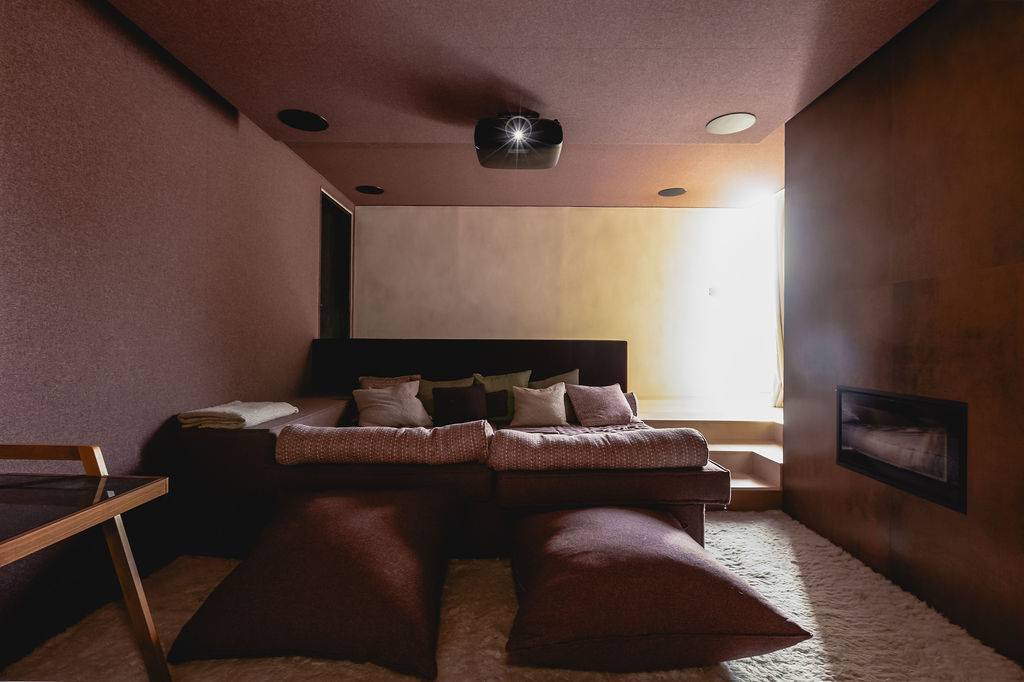 Dark moody cinema room with plush double bed seating, projector setup, and dusky mauve walls, Love Locations GU32.