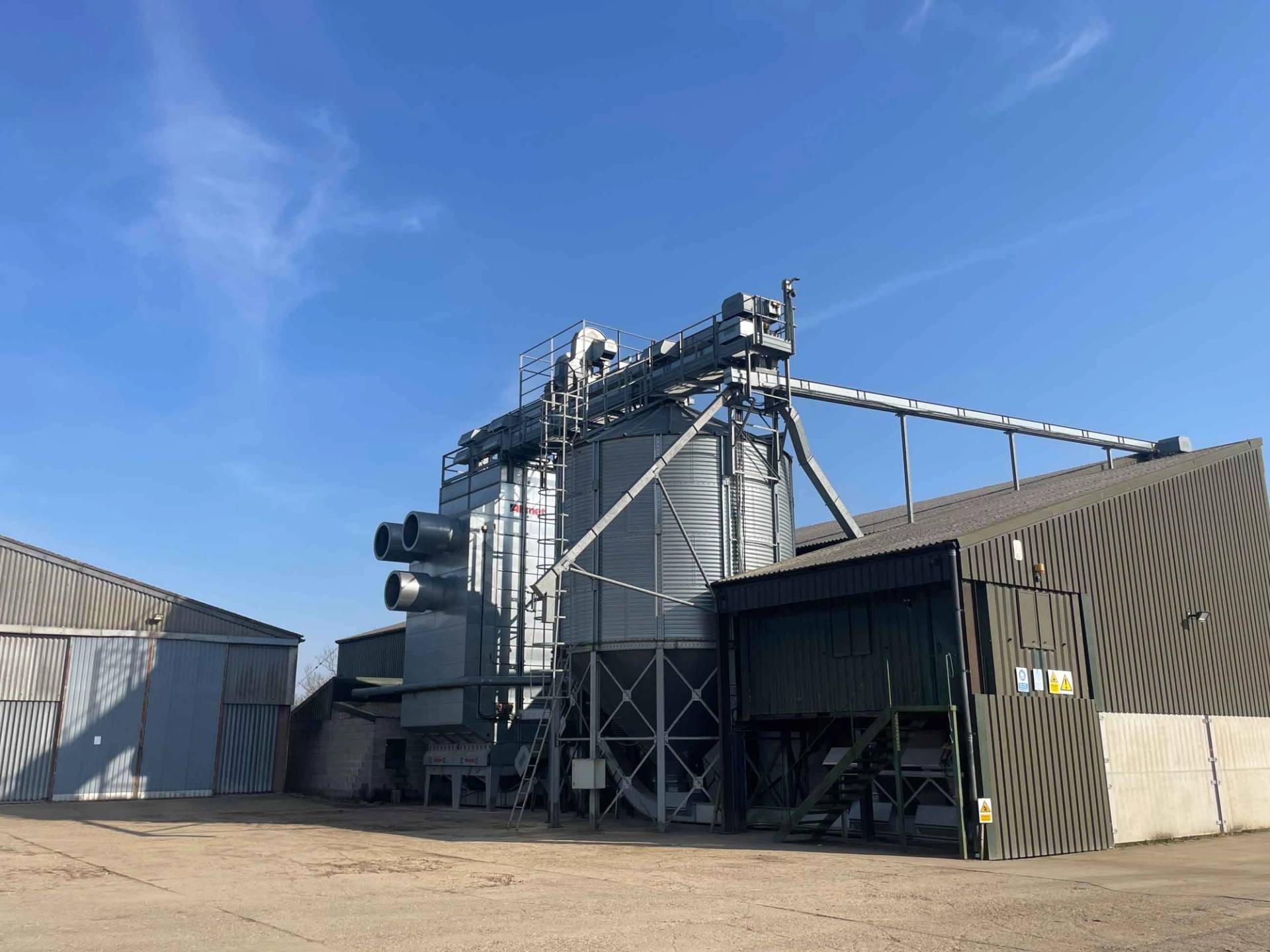 Industrial grain processing tower and modern agricultural sheds on a historic Northamptonshire estate in NN17, the ultimate versatile production location via Love Locations.