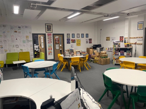 Love Locations modern classroom shoot space RG30: Interactive learning room featuring round white tables, colorful plastic chairs, and educational displays, ideal for children's brand commercials.