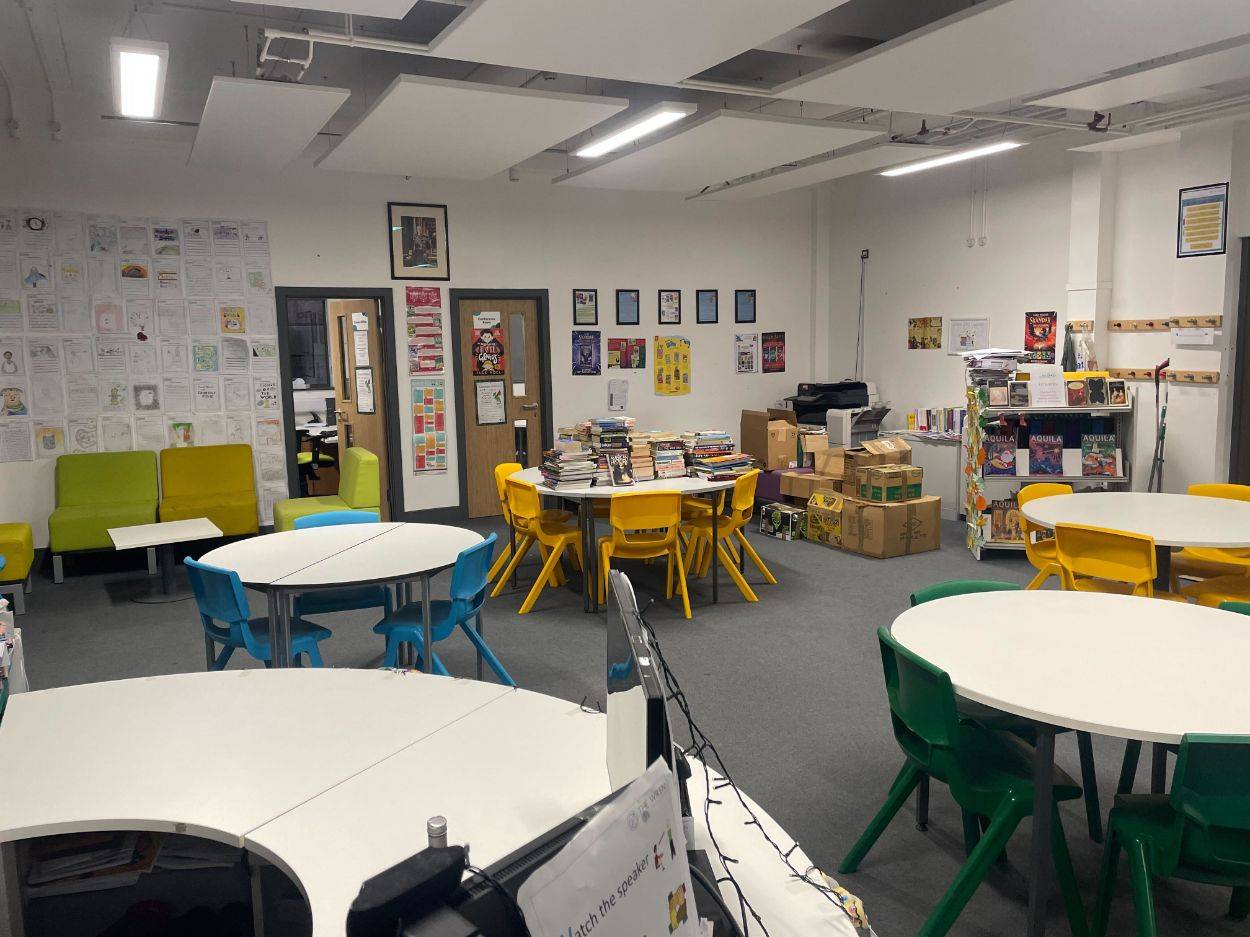 Love Locations modern classroom shoot space RG30: Interactive learning room featuring round white tables, colorful plastic chairs, and educational displays, ideal for children's brand commercials.