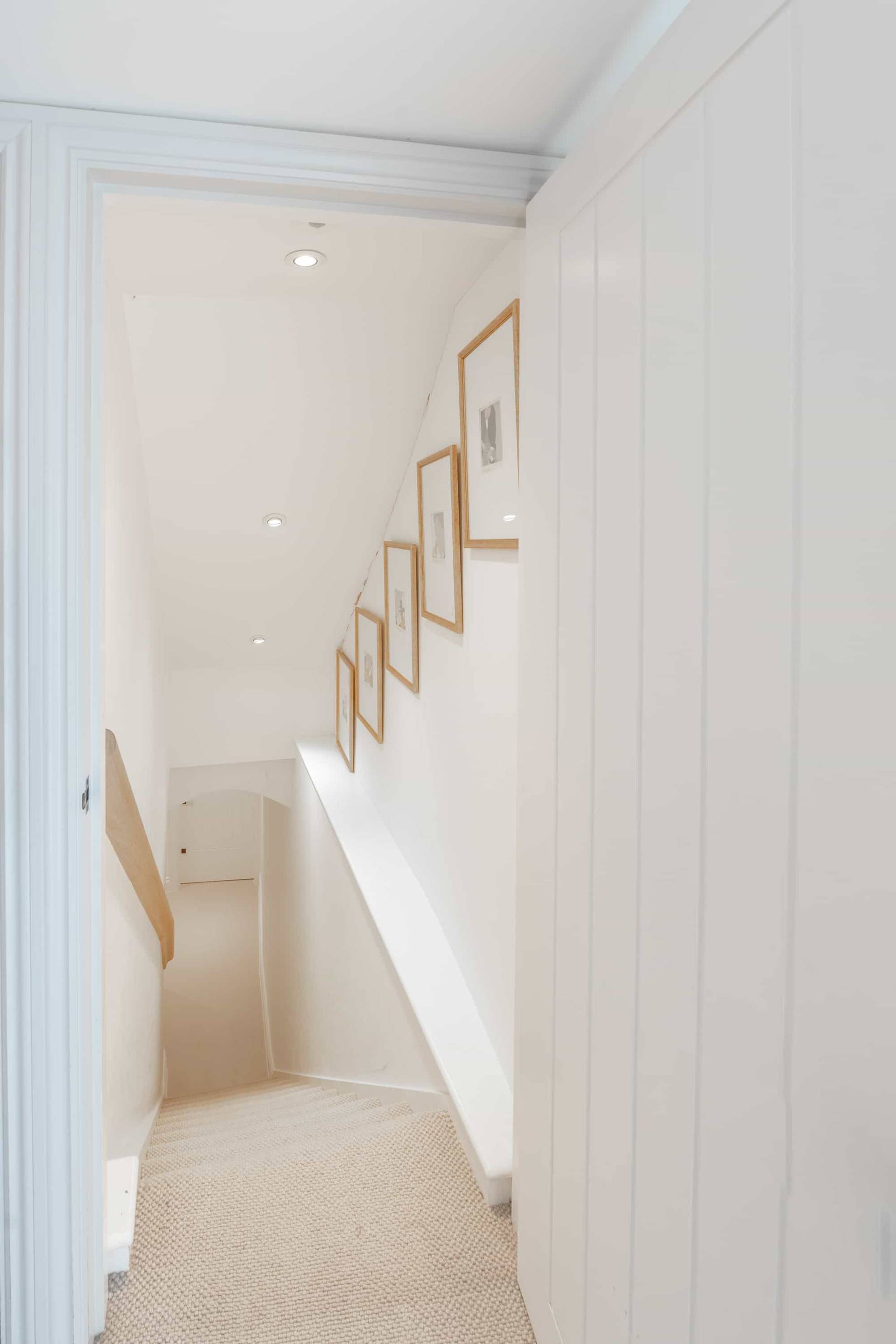 Minimalist white staircase hallway with wooden pegs and light oak step treads, Love Locations GU28.