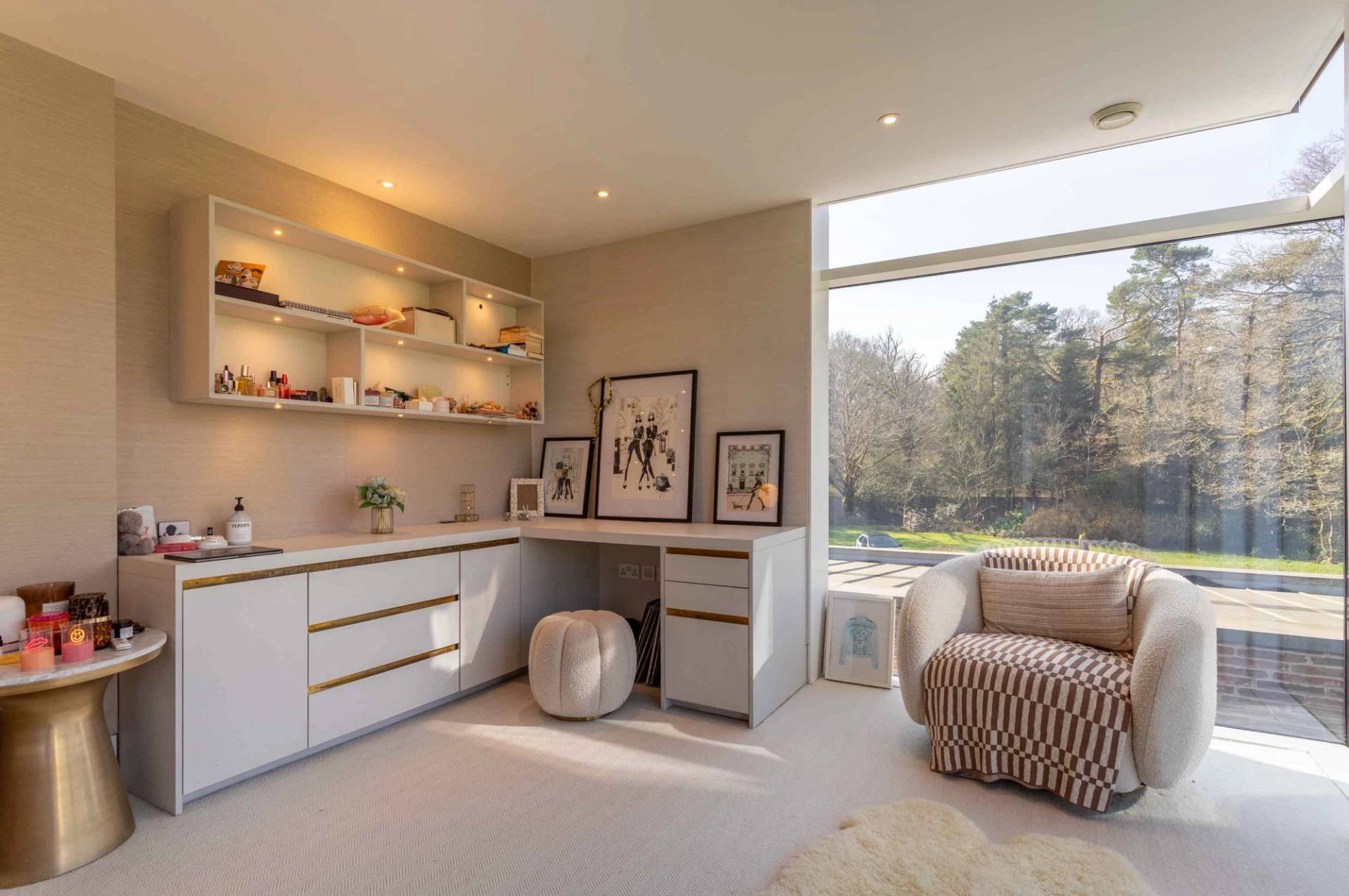 Love Locations luxury dressing room location Surrey GU8: Custom built-in vanity writing desk and shelving units positioned underneath a massive picture window, perfect for talent prep and vlogs.