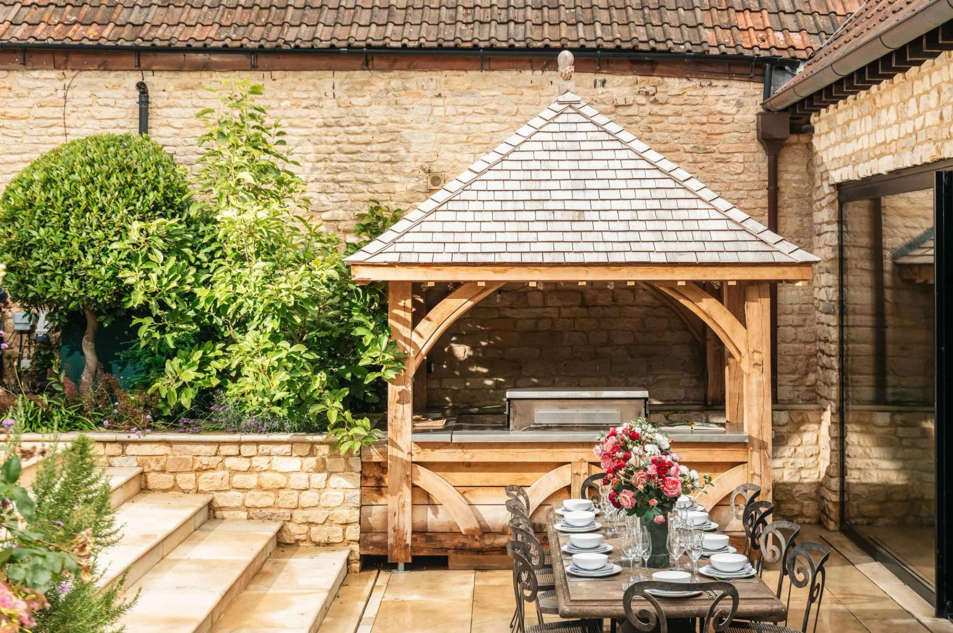 Timber gazebo outdoor kitchen and covered dining area in a landscaped garden location through Love Locations.