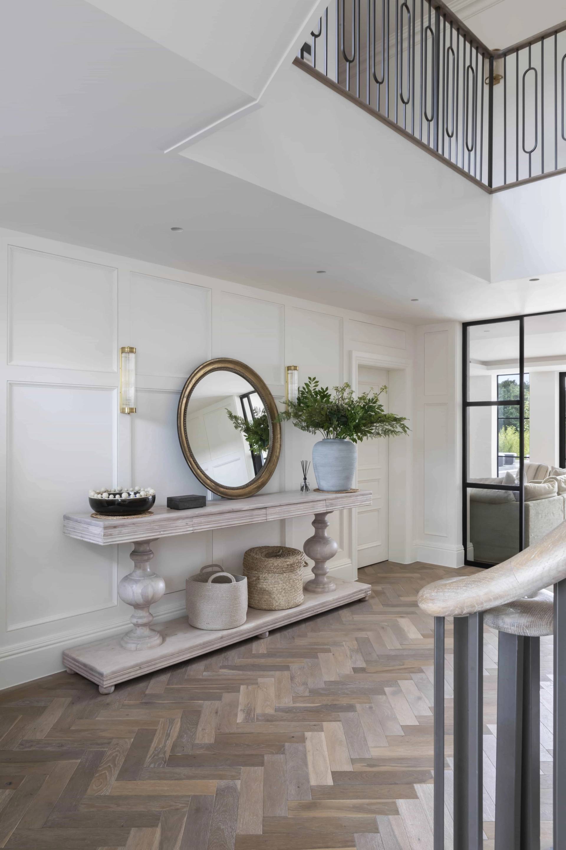 Grand entrance hall console table styled with a large oval mirror and decorative vase set on herringbone flooring, Love Locations HP18.