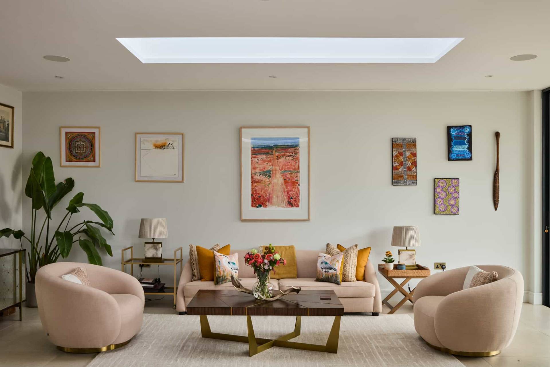 Light-filled living room featuring neutral sofas, plush blush armchairs, and contemporary artwork, ideal for family brand advertising, Love Locations.