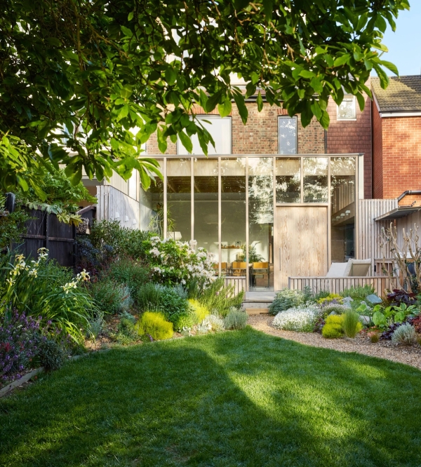 Lush green landscaped garden looking back towards a timber-framed glass house extension in Walthamstow, Love Locations E17.